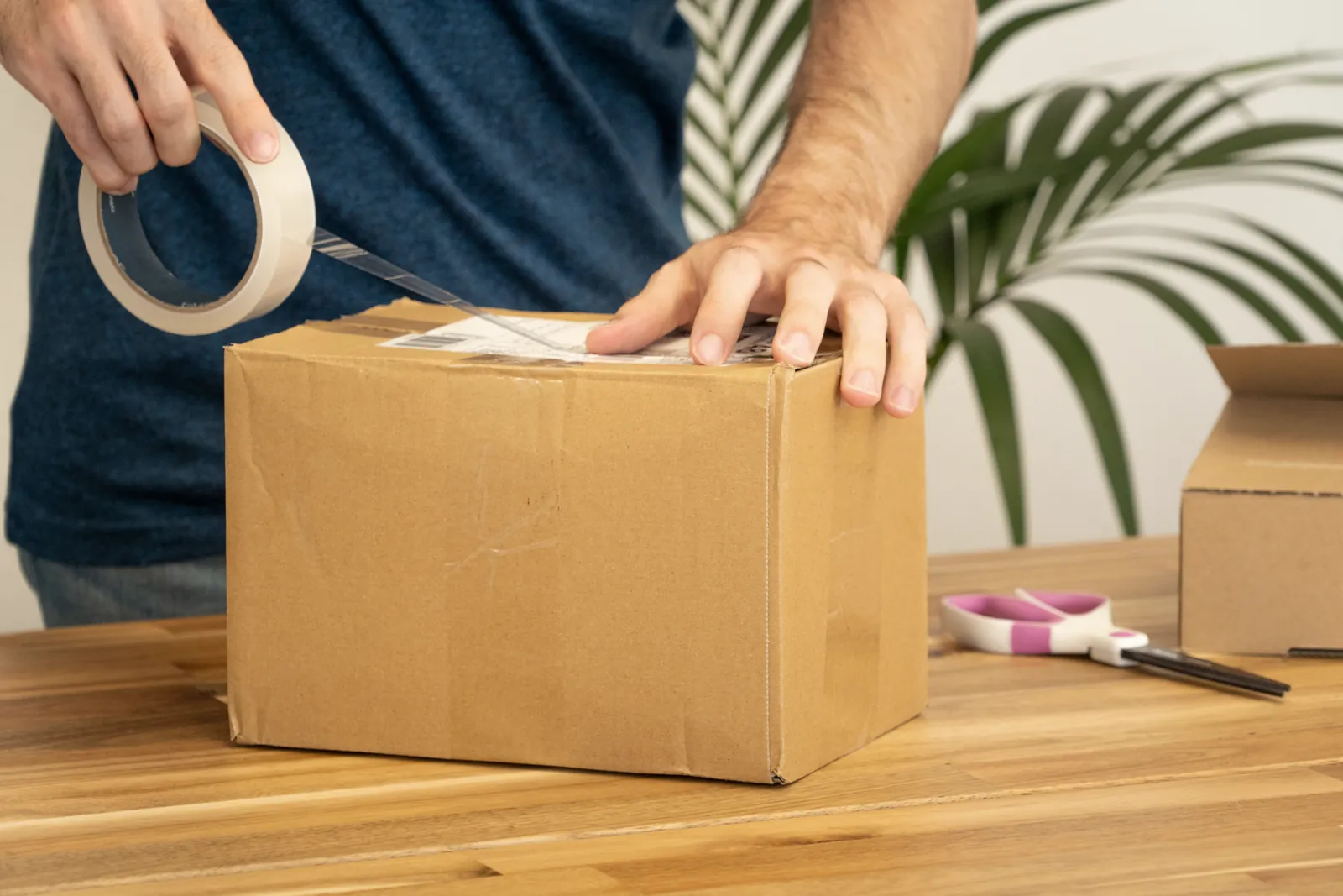 Manos cerrando con cinta una caja de cartón